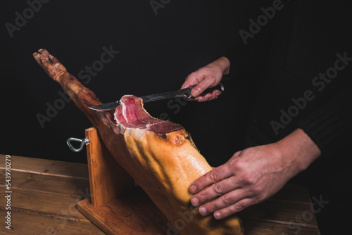 closeup chef cutting ham with knife.