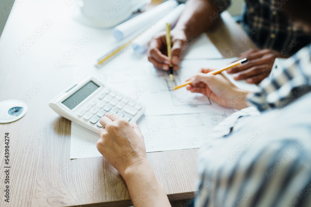 Engineers are consulting the team to design an architectural structure for clients with blueprints and building models to work at office Engineers are consulting the team to design an architectural structure for clients with blueprints and building models to work at office