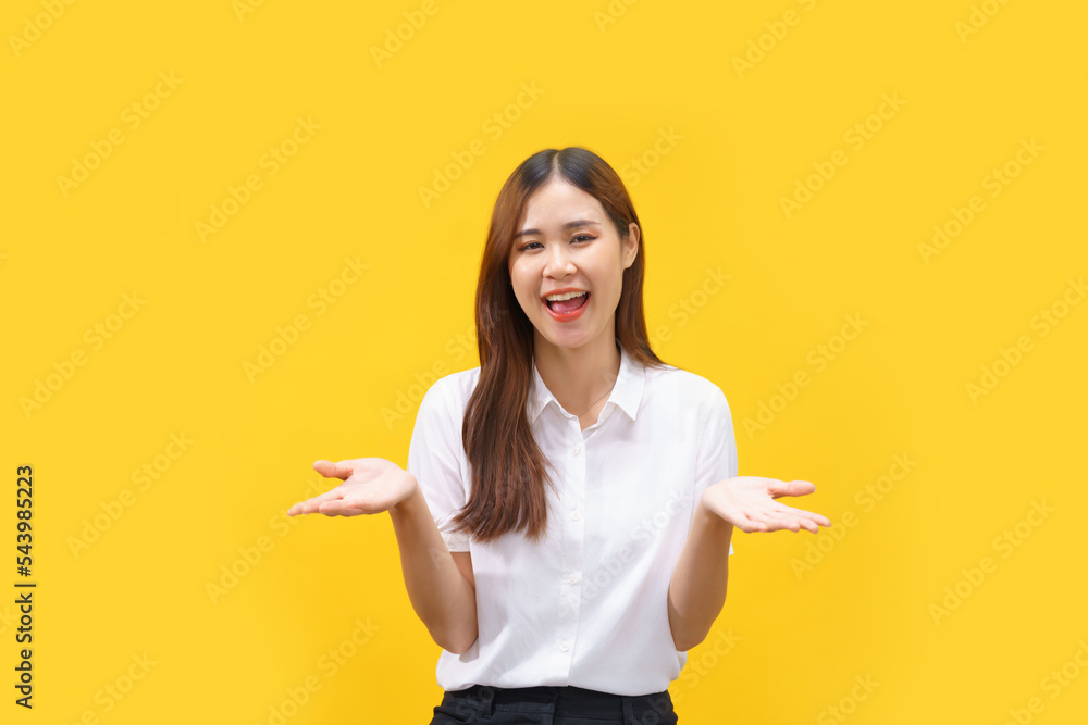 Women are smiling and holding something in both hands while standing on isolated yellow background Women are smiling and holding something in both hands while standing on isolated yellow background
