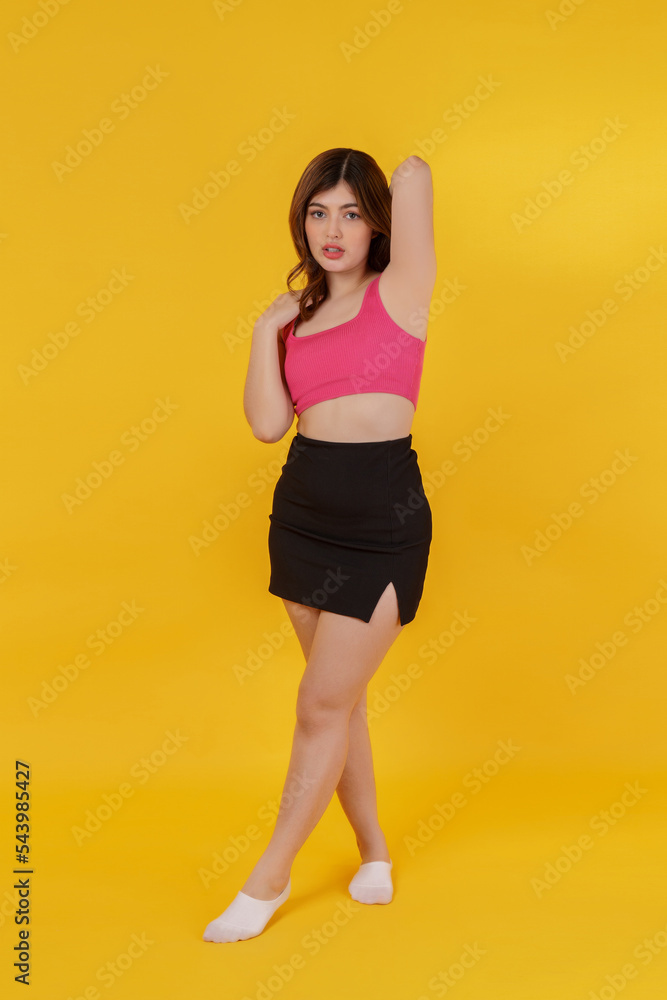 Full length portrait of a beautiful young woman posing isolated over yellow background