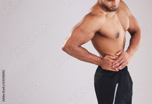 Fitness, sports and man with waist pain, topless in studio background. Sport injury, hurt muscle and a male model with muscular body in studio holding his side, health and body care at gym workout.