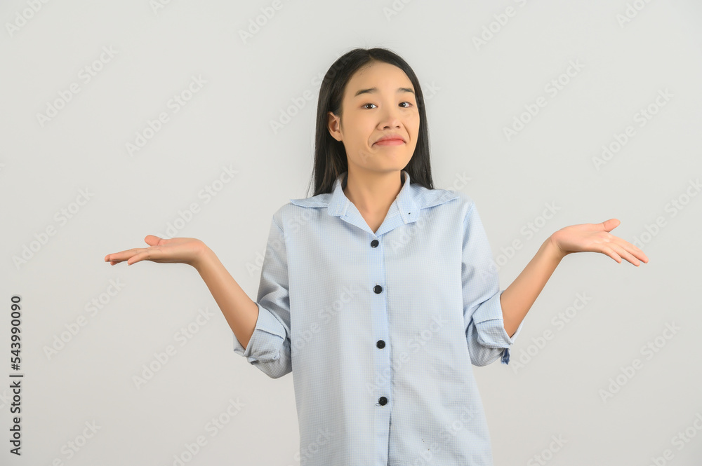 Portrait of confused young asian woman in blue shirt shrugging shoulders in bewilderment isolated on white background Portrait of confused young asian woman in blue shirt shrugging shoulders in bewilderment isolated on white background