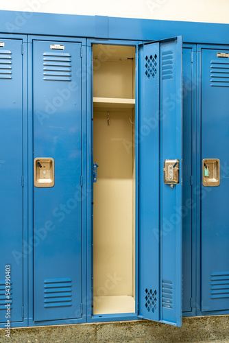 Single open empty blue metal locker along a nondescript hallway in a typical US High School. No identifiable information included and nobody in the hall.