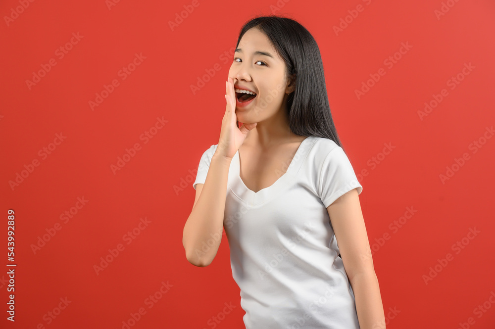 Portrait of Young asian woman in white t-shirt shout story or making announcement isolated on red background