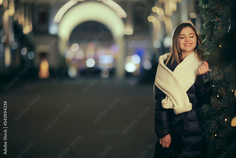 girl christmas lights evening decorated city, a young model on the background of urban decorations and garlands, night city lights