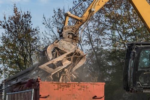 Ein Bagger belädt einen Schüttcontainer mit Holzabfall photo