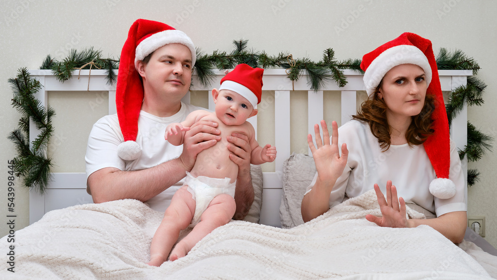 Obraz premium Wife refuses to look after baby on bed decorated for christmas and new year, family couple in home bedroom