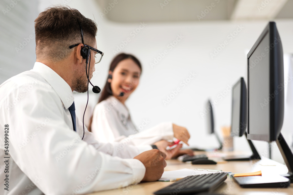 Group of happy call center smiling business operator customer help support team phone services agen working and talking with headset on desktop computer at call center office Group of happy call center smiling business operator customer help support team phone services agen working and talking with headset on desktop computer at call center office