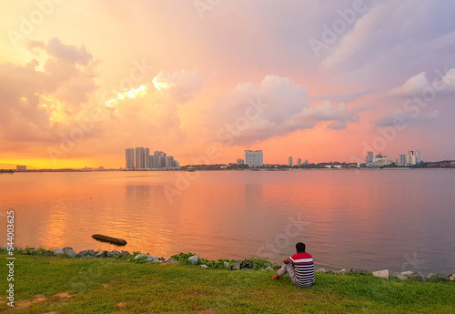 Foto A man sits alongside the Kranji Reservoir admiring the beautiful sunset