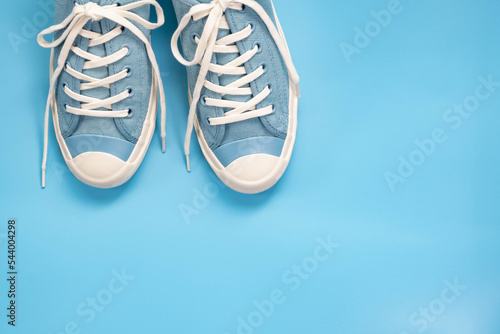 Flat lay of soft blue color canvas shoe on soft blue background with copy space