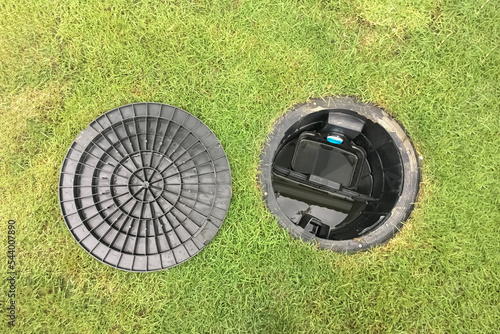 Image of a septic tank grease trap for home use to help collect light liquids such as fats, oils, and grease from the kitchen buried underground with green grass cover.