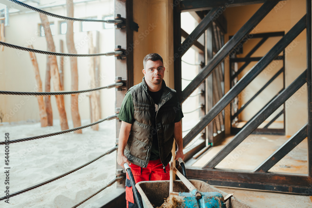 Foto de Caretaker with down syndrome in zoo pushing wheelbarrow after