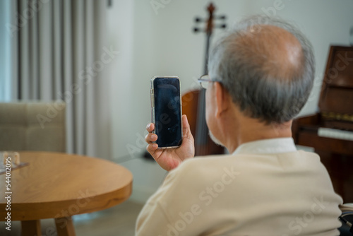 Senior man sitting on wheelchair using smartphone to speak to him children and grandkids online from home,Making video call with relatives.
