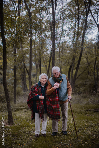 Senior couple walking together in autumn forest.