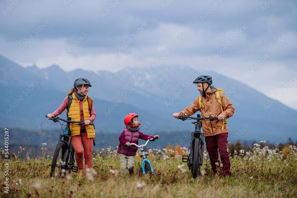 Young family with little daughter at bicycles, in the middle of autumn nature.Concept of a healthy lifestyle.