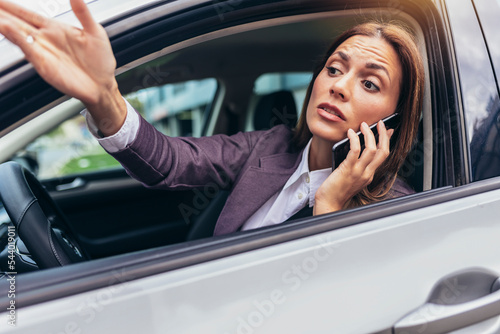 Angry young woman using phone pissed off by drivers in front of her and gesturing with hands