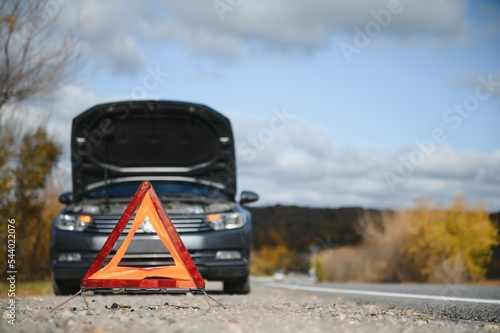 breakdown triangle stands near a broken car.