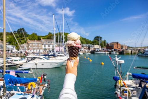 UK, England, Padstow, Personal perspective of woman holding ice cream against town harbor photo