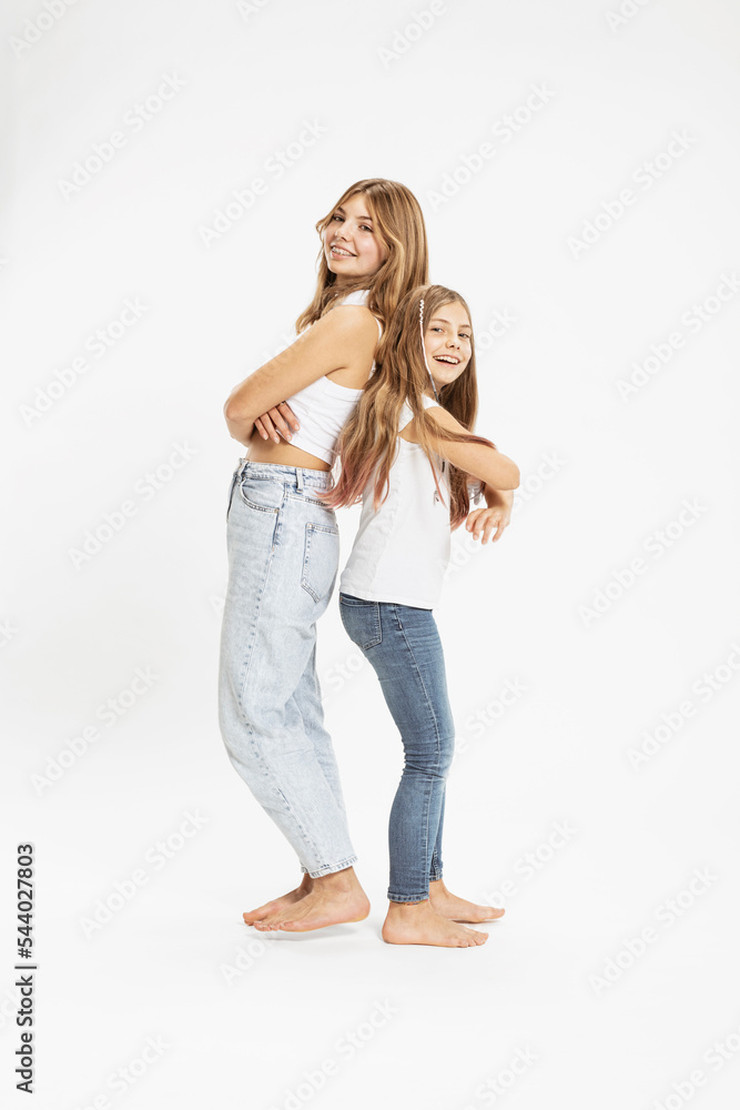 Smiling sisters standing with arms crossed together in studio