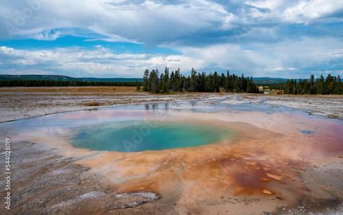 Scenic view of beautiful Grand Prismatic Spring with cloudy sky in background. Geothermal landscape in Midway Geyser Basin during summer. Famous tourist attraction at Yellowstone national park.