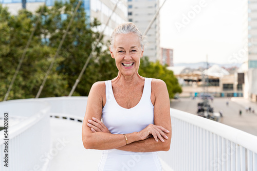 Happy woman with arms crossed standing on footbridge