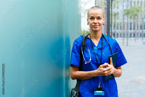 Female nurse with shaved head holding tablet PC photo