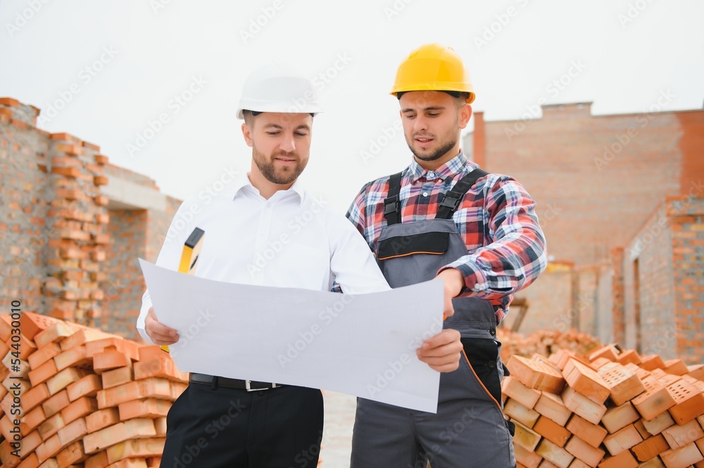engineer architect with hard hat and safety vest working together in team on major construction site engineer architect with hard hat and safety vest working together in team on major construction site