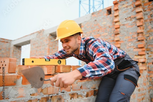 Print op canvas construction mason worker bricklayer installing red brick with trowel putty knife outdoors