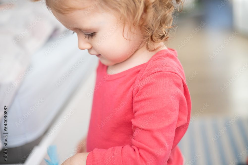 toddler girl looks down  - obrazy, fototapety, plakaty 