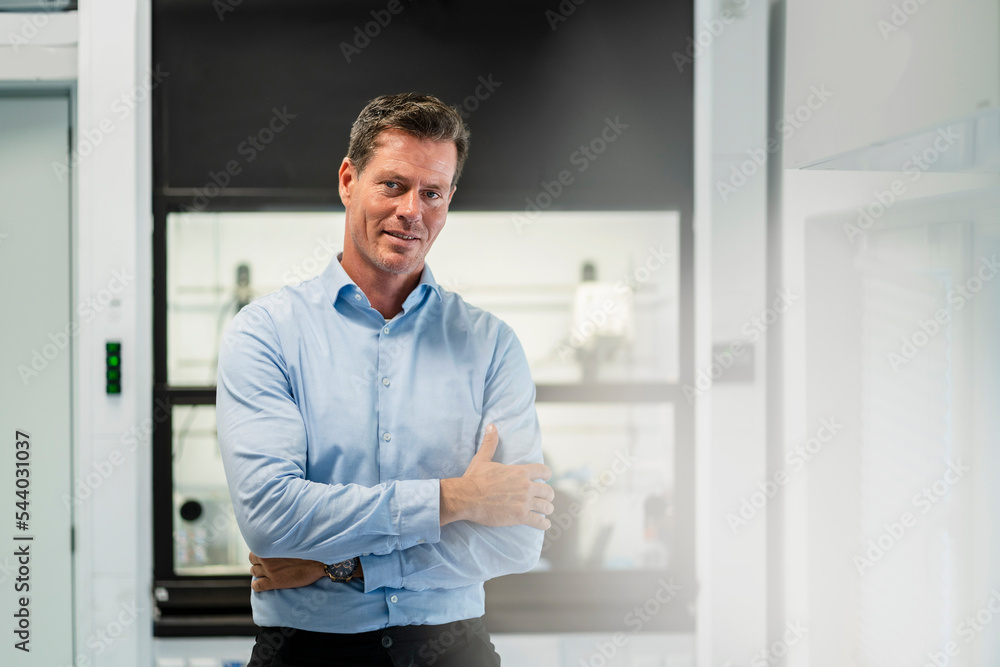 Smiling businessman with arms crossed standing at industry Smiling businessman with arms crossed standing at industry