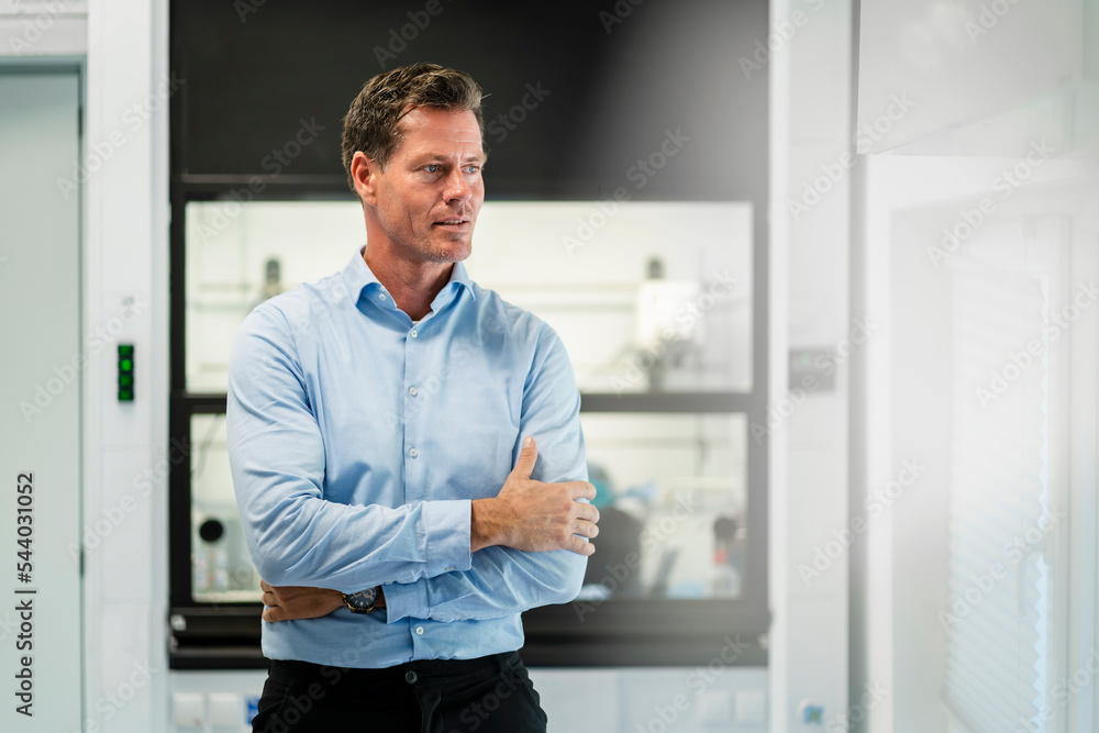 Mature businessman with arms crossed standing at industry Mature businessman with arms crossed standing at industry
