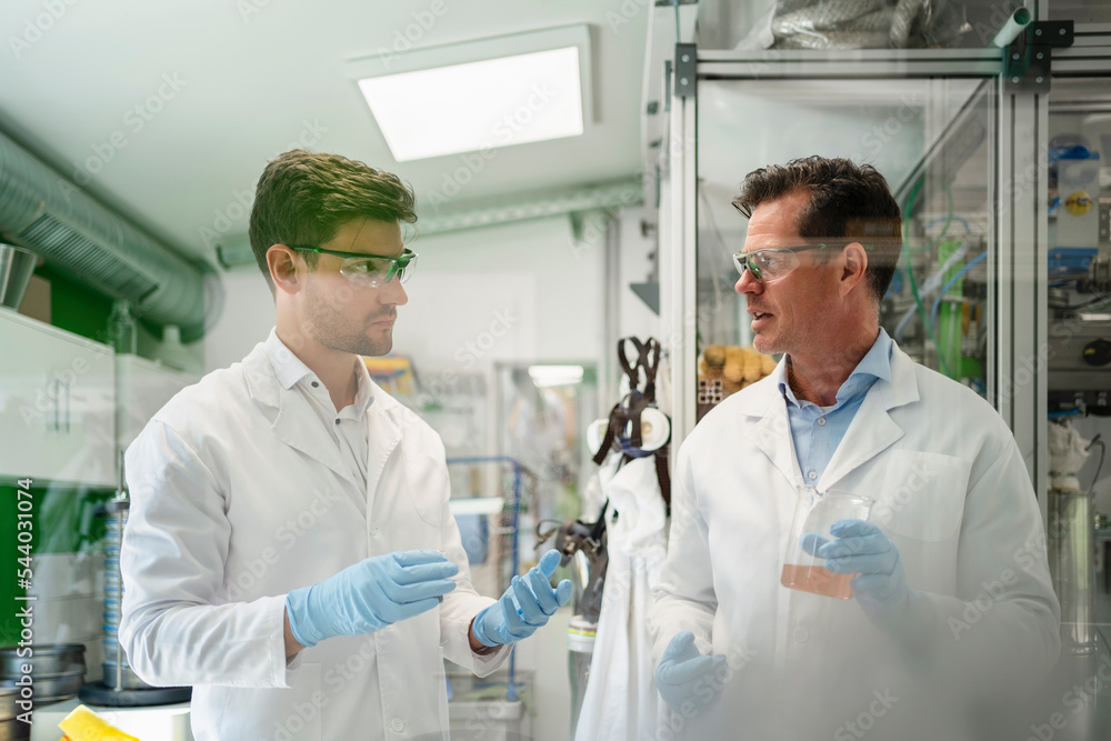 Scientists discussing with colleague and doing thermolysis experiment in laboratory Scientists discussing with colleague and doing thermolysis experiment in laboratory