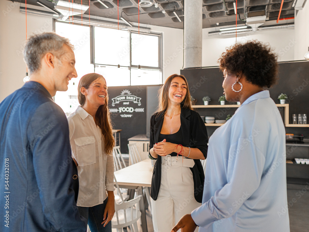 Happy businessman talking with businesswomen in cafeteria Happy businessman talking with businesswomen in cafeteria
