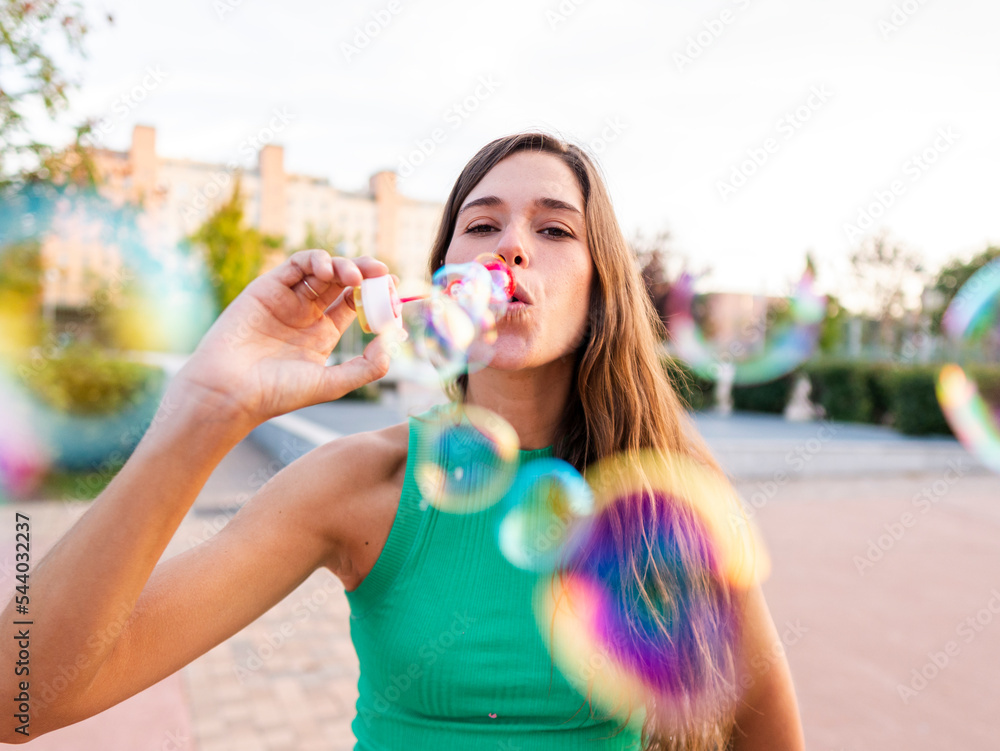 Woman blowing colorful bubbles at footpath Woman blowing colorful bubbles at footpath