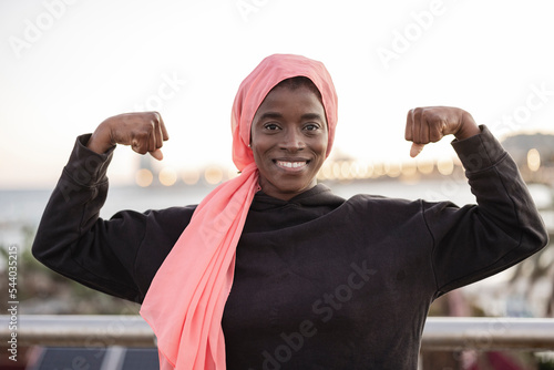 Portrait of a young african woman wearing a pink headscarf for cancer standing strong photo