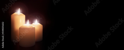 White church candles burning in the dark night background