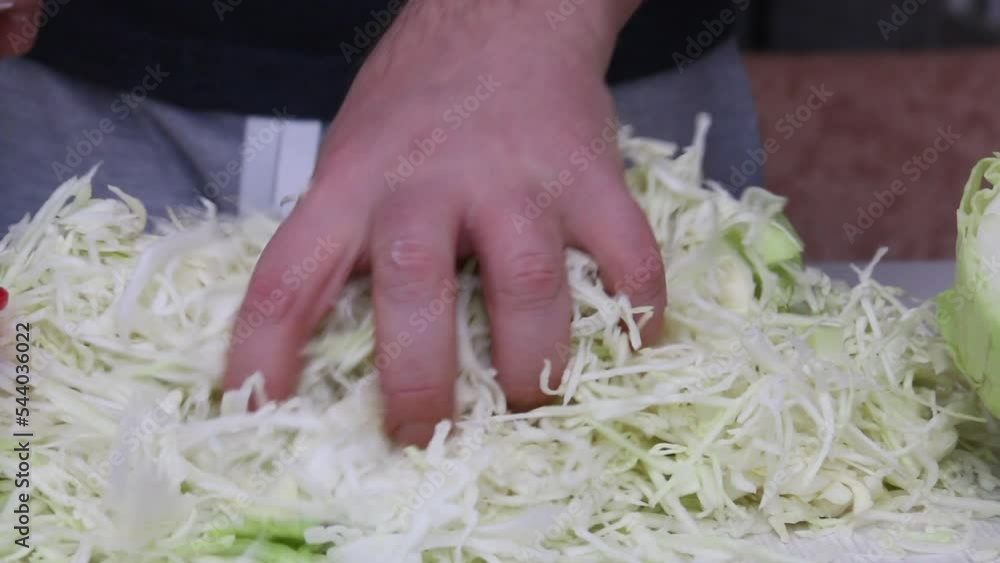 A man mixes chopped cabbage with his hands. Sauerkraut in a jar. Harvesting vegetables for the winter. The camera moves on the slider. Close-up. A man mixes chopped cabbage with his hands. Sauerkraut in a jar. Harvesting vegetables for the winter. The camera moves on the slider. Close-up.