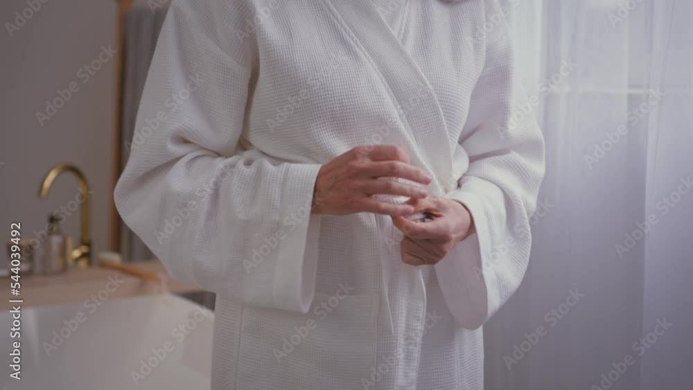 Close up cropped view unrecognizable old Caucasian woman unknown senior mature lady female in bathroom after bathing hygiene procedure in bath ties belt on white soft cozy comfortable bathrobe cloth Close up cropped view unrecognizable old Caucasian woman unknown senior mature lady female in bathroom after bathing hygiene procedure in bath ties belt on white soft cozy comfortable bathrobe cloth