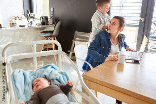 Gestresste Mutter im Home Office mit Baby und Sohn photo