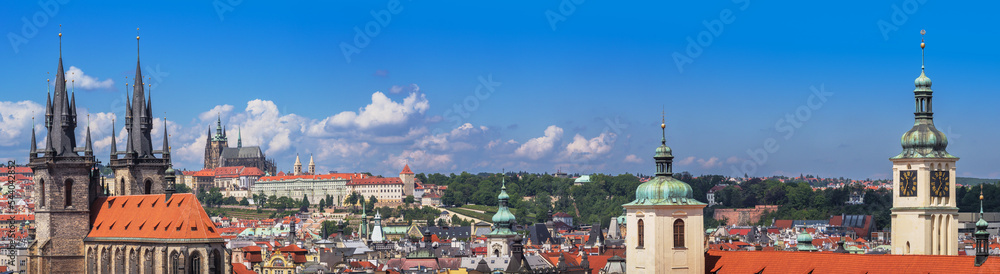 Naklejka premium Panorama of Prague city with medieval castle on skyline, old architecture, Cathedrals, gothic towers and spires. Wide landscape of Praga, view on the town with red roofs on houses and top landmarks.