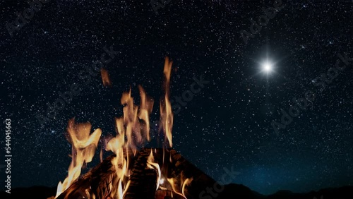 bonfire burns at night against the background of mountains and sea with bright christmas stars photo