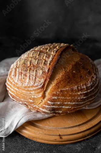 Homemade sourdogh whole round bread on dark background. Home baking concept.