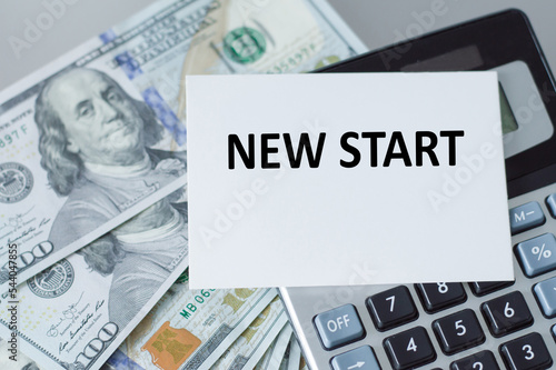 New Start text on a card on the background of a calculator and dollar bills on the table