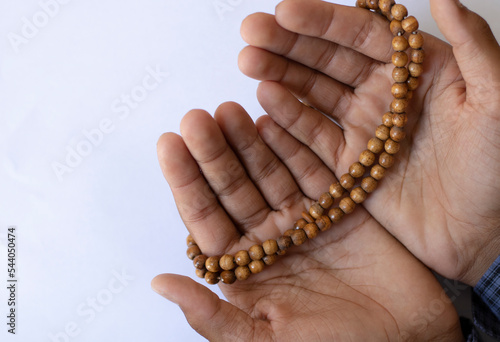 Asian young boy prays with open hands on a white background. Boy praying to god with the praying beads.