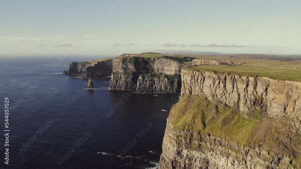 Cinematic aerial of Cliffs of Moher, Ireland during golden hour on sunny day. Flying sideways, epic view over coast line with Pinnacle Rock and O'Brien's Tower ocean waves crashing against rocks. 4K Cinematic aerial of Cliffs of Moher, Ireland during golden hour on sunny day. Flying sideways, epic view over coast line with Pinnacle Rock and O'Brien's Tower ocean waves crashing against rocks. 4K