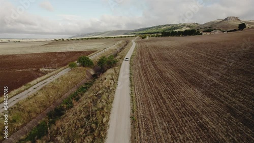 Drone following a silver car on a dirtroad between fields of farmlands in Italy in 4k photo