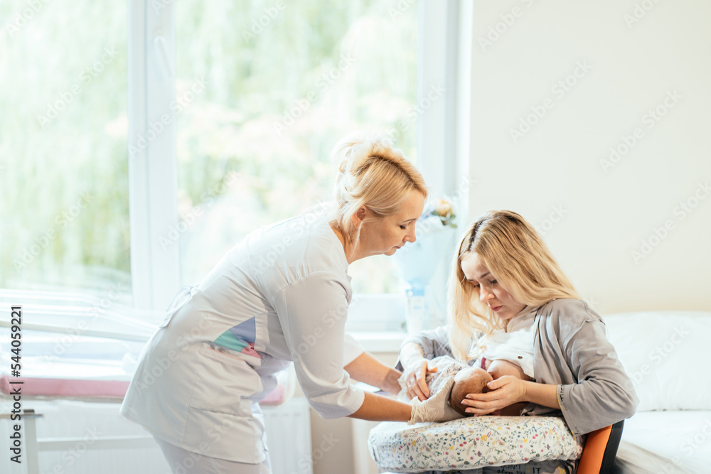 Midwife supporting a breastfeeding mother with her newborn baby boy in