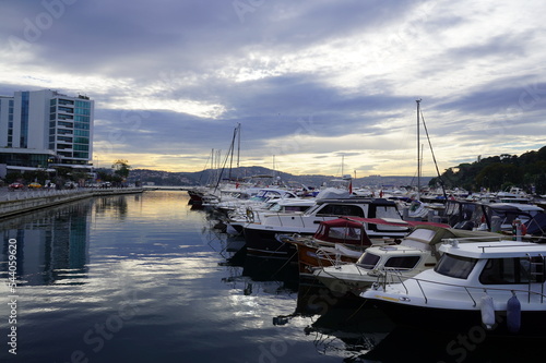 Sailboats at Tarabya yacht marina in Istanbul. Reflection of yachts and hotel. Blue sky and natural white clouds.