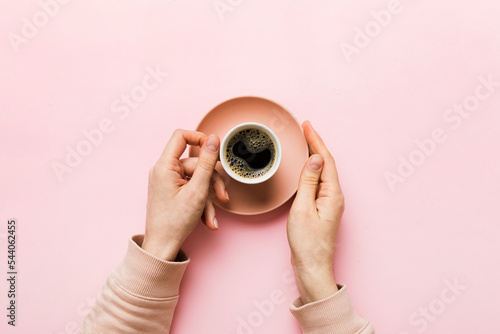 Minimalistic style woman hand holding a cup of coffee on Colored background. Flat lay, top view cappuccino cup. Empty place for text, copy space. Coffee addiction. Top view, flat lay