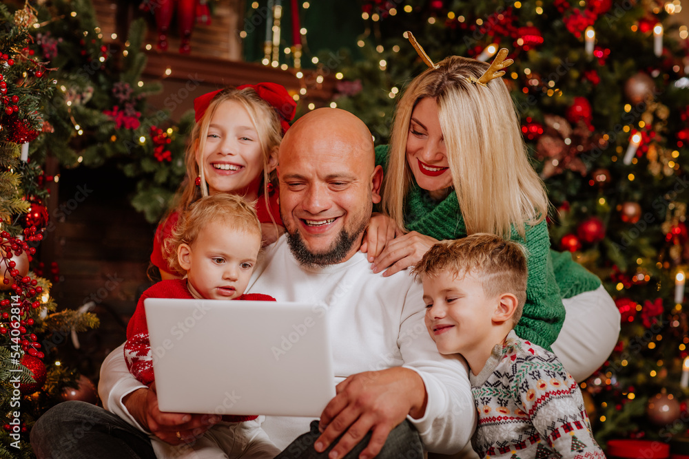 Big family of five people are doing online shopping by laptop in Christmas room Big family of five people are doing online shopping by laptop in Christmas room